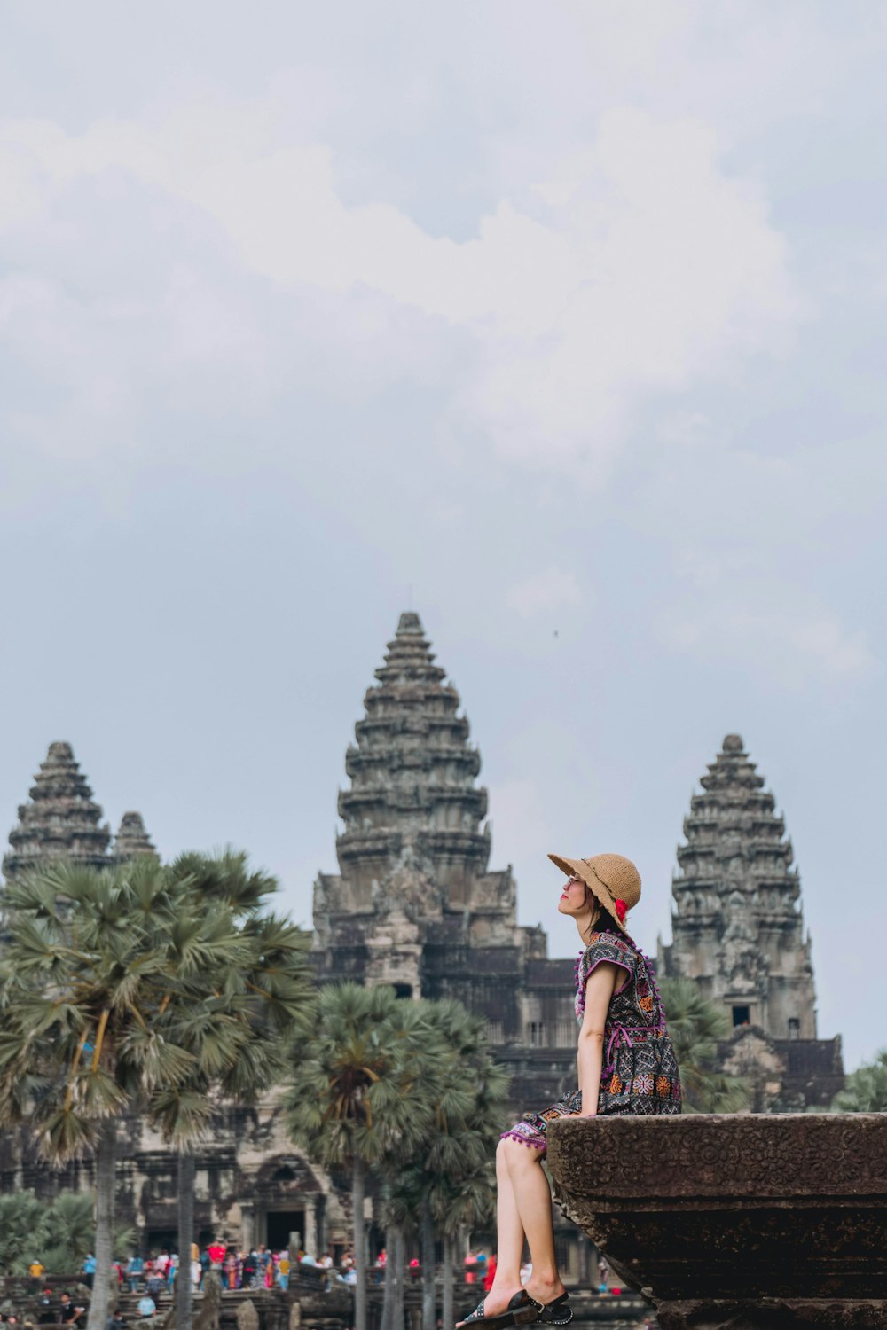 a person in a hat and dress standing in front of a statue