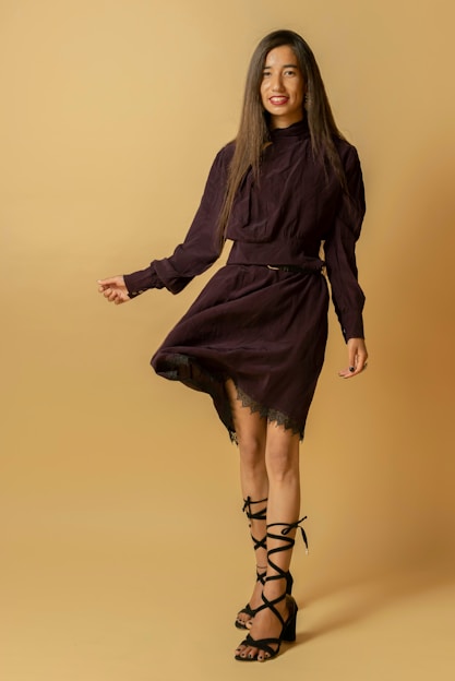 A vibrant display of a model wearing a flowing purple dress paired with chic accessories, set against a soft lavender background.