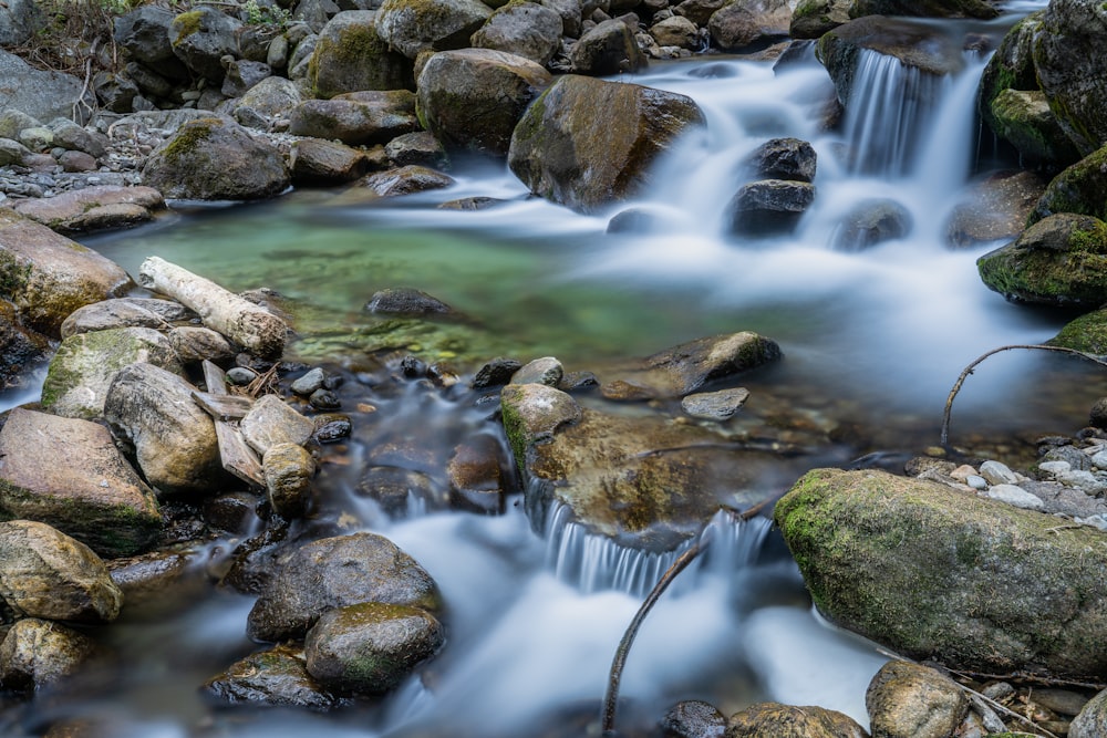 um riacho de água com rochas e uma cachoeira