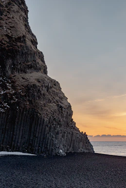 a rocky cliff next to a body of water