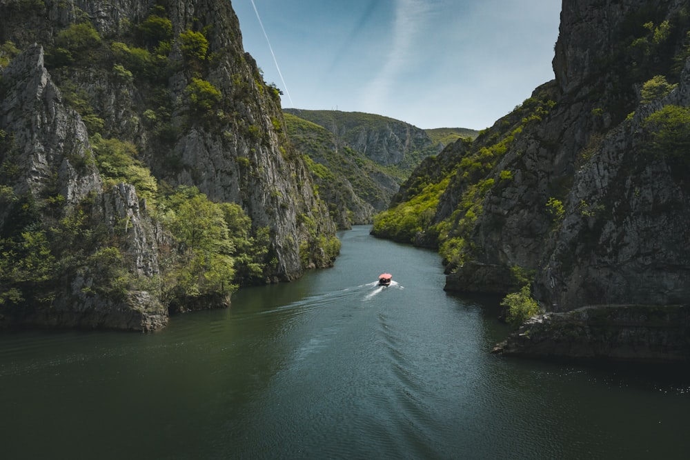 a person in a boat in a river between rocky cliffs