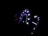 A detailed shot of a car dashboard with illuminated gauges at night.