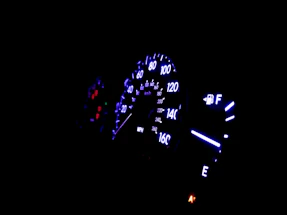 Close-up of a sleek car dashboard illuminated by neon blue lights at night.
