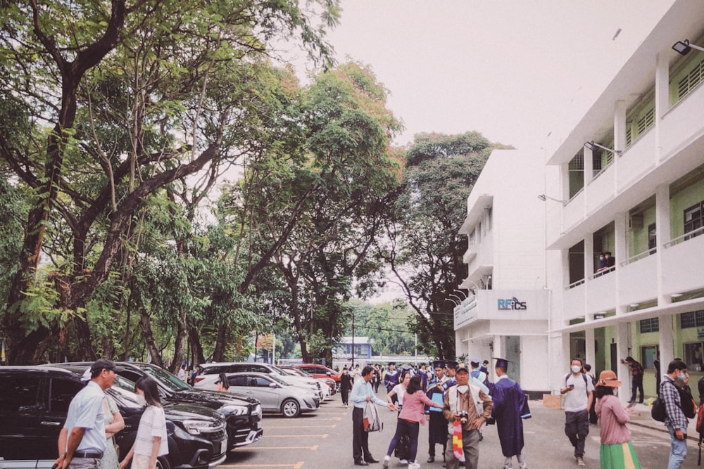 a group of people walking on a street with cars and trees