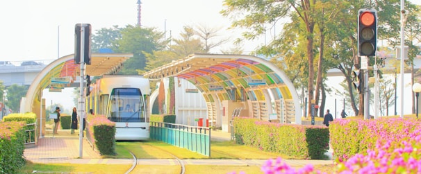 A tram conductor coordinating with team members at a sunny urban tram stop.
