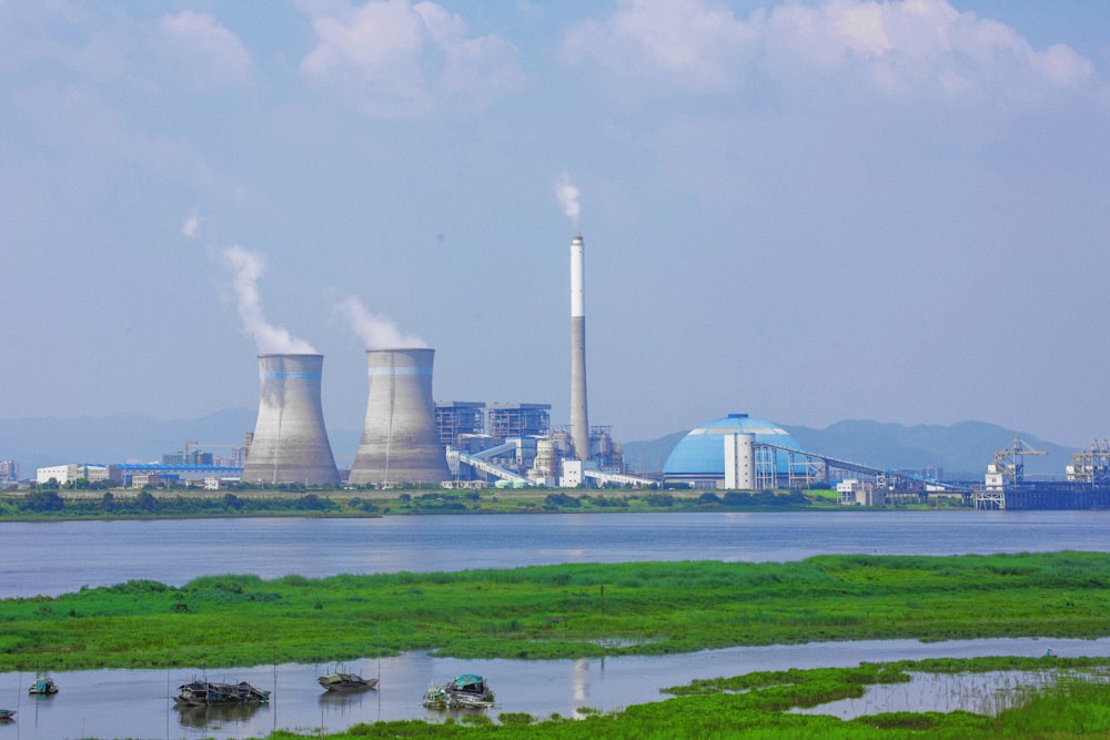 a group of smokestacks by a body of water