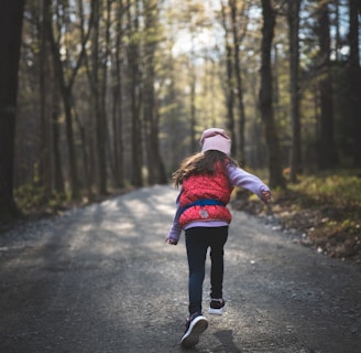 en flicka springer på en grusväg i skogen