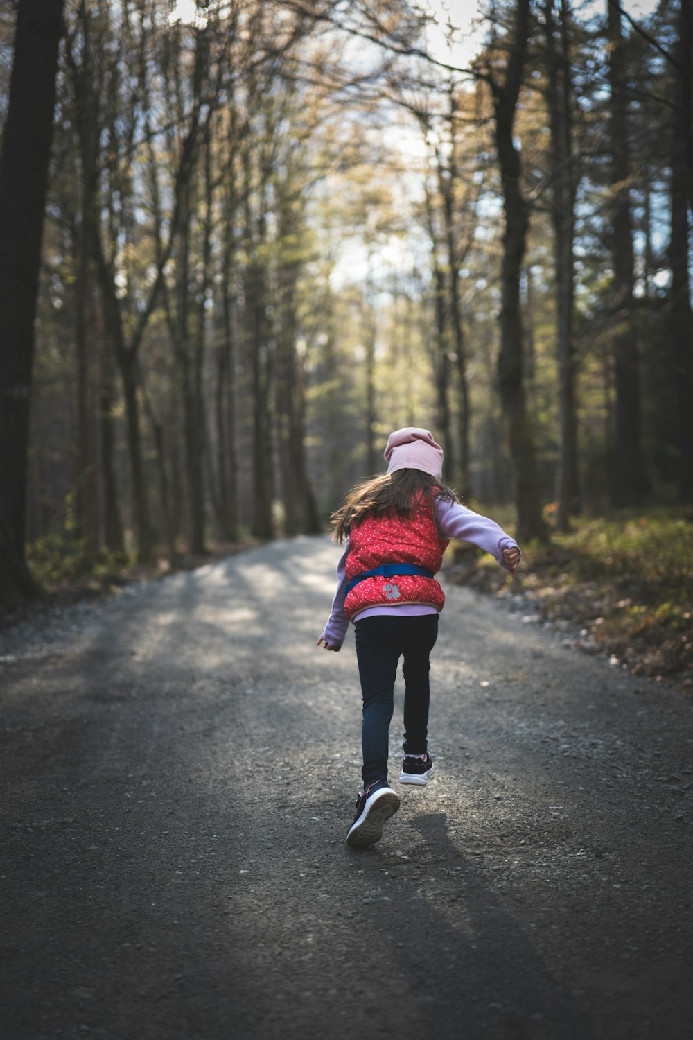 a girl running on a road in the woods