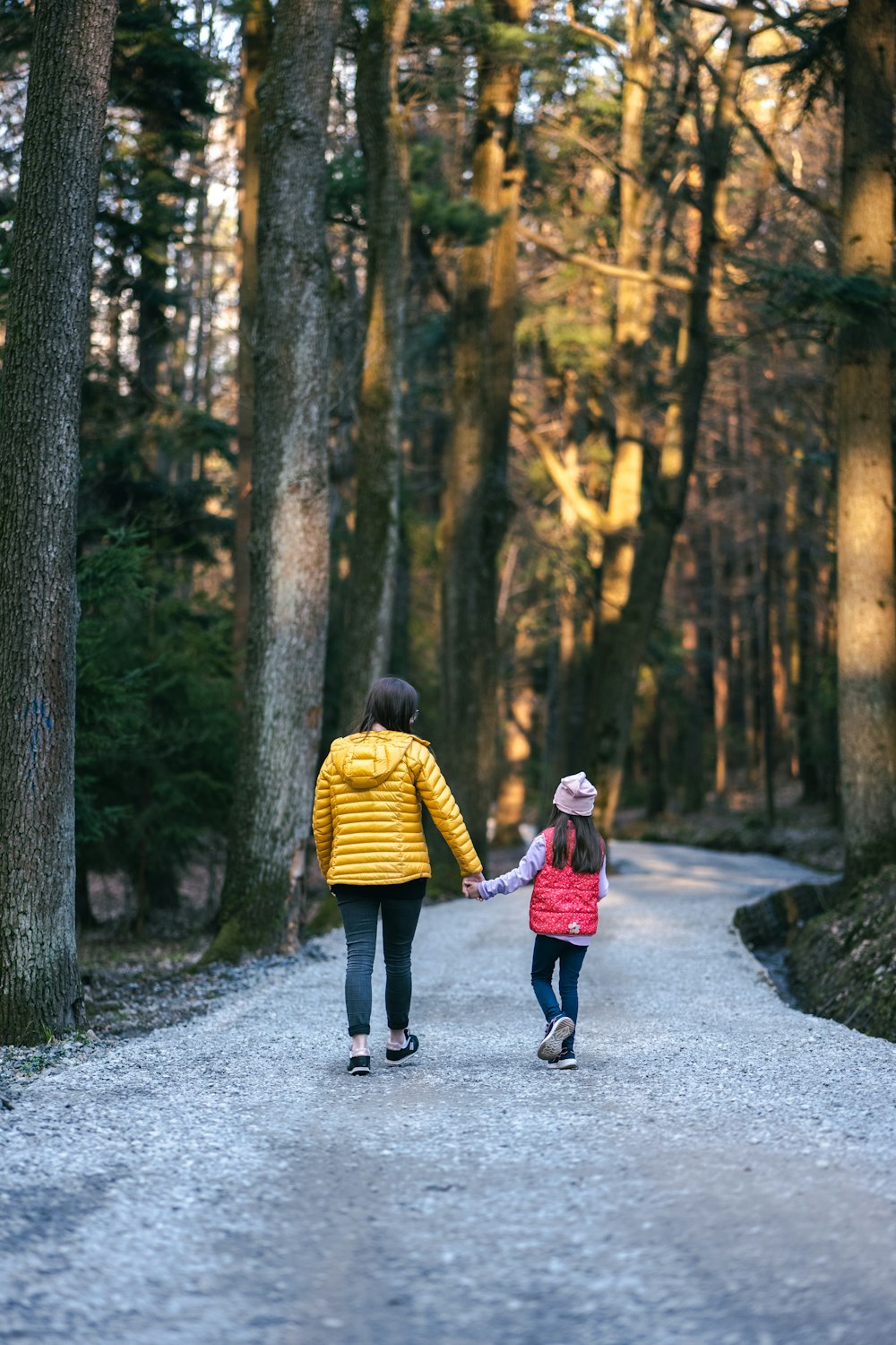 a person and a child walking on a path in the woods