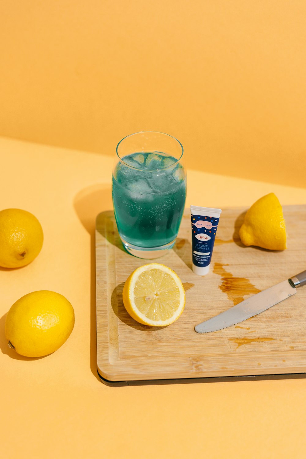 un vaso de agua y limones en una tabla de cortar