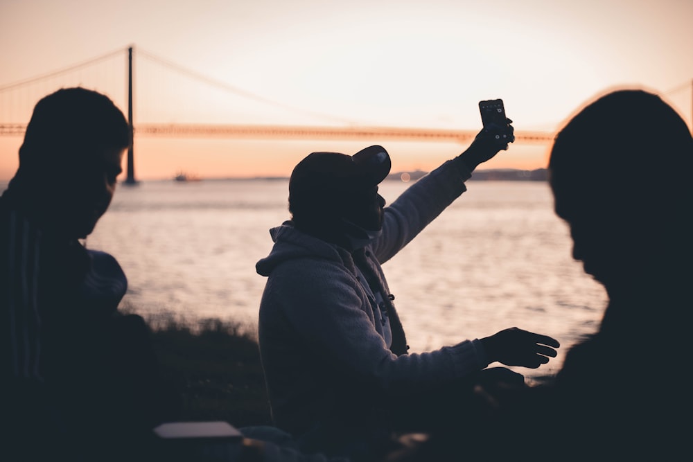 a group of people sitting on a bench looking at a sunset