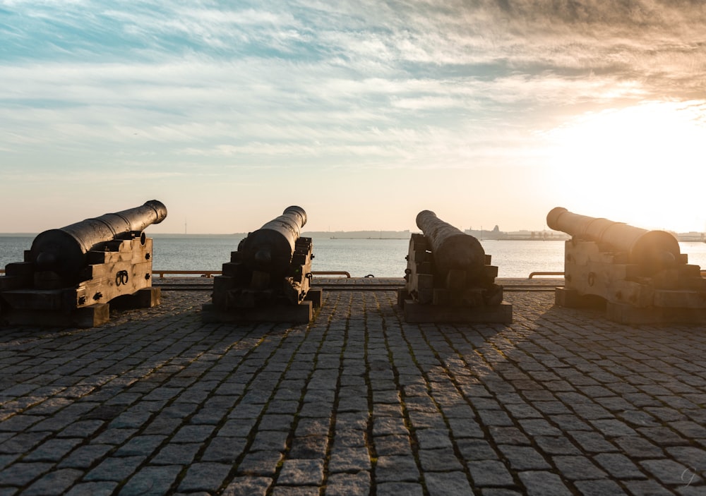 a group of cannons on a brick surface by the water