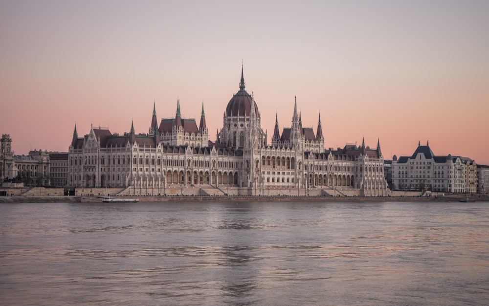 um corpo de água com um grande edifício ao fundo com o edifício do Parlamento húngaro ao fundo