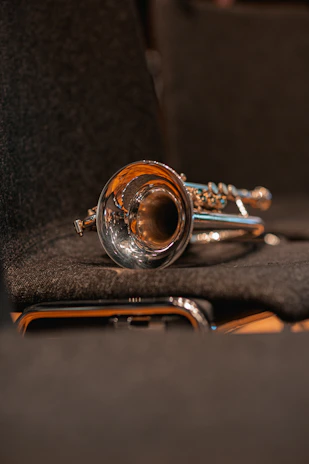 Close-up of a shiny trumpet resting on sheet music with soft stage lighting