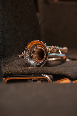 Close-up of a polished trumpet resting on sheet music inside a warmly lit studio.
