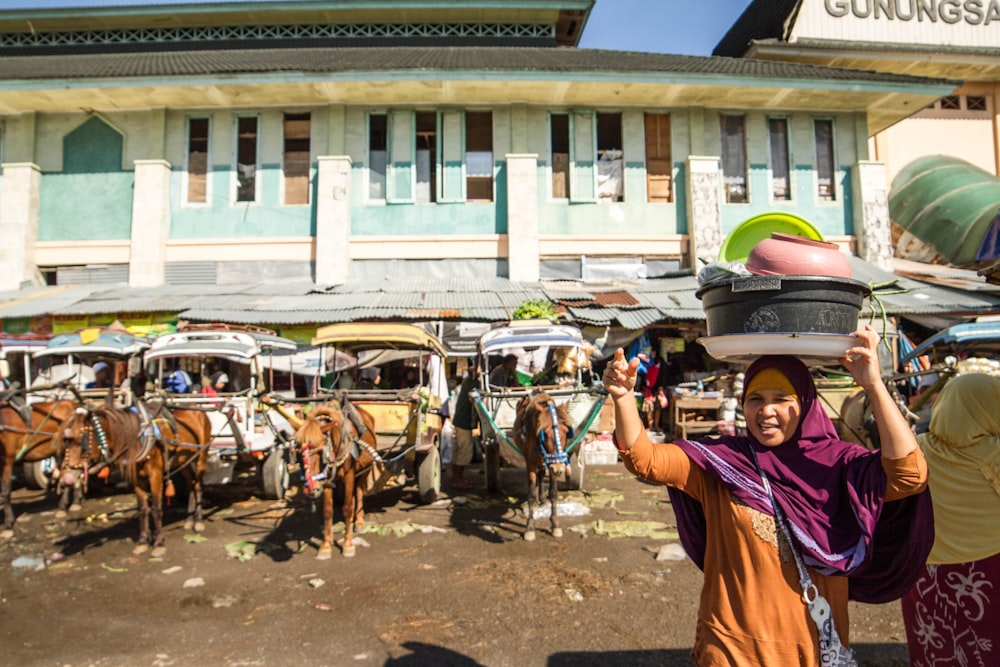 a person holding a gun in front of a row of horses