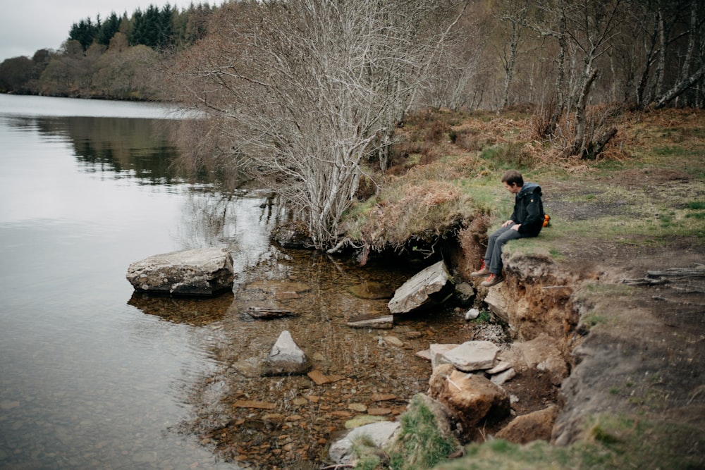 a person sitting on a rock by a river