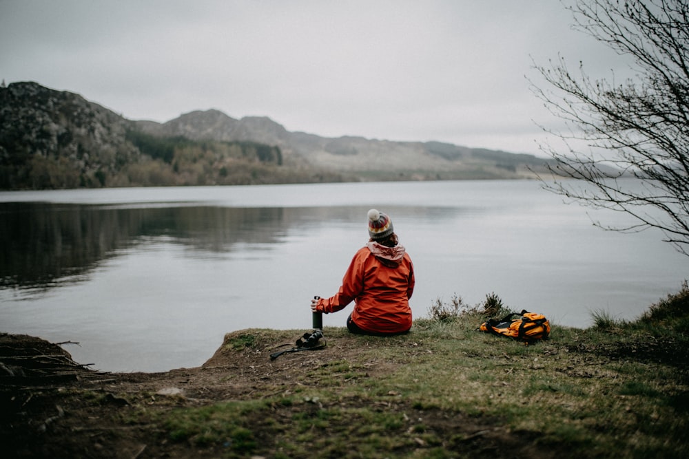 a person sitting on a rock by a body of water