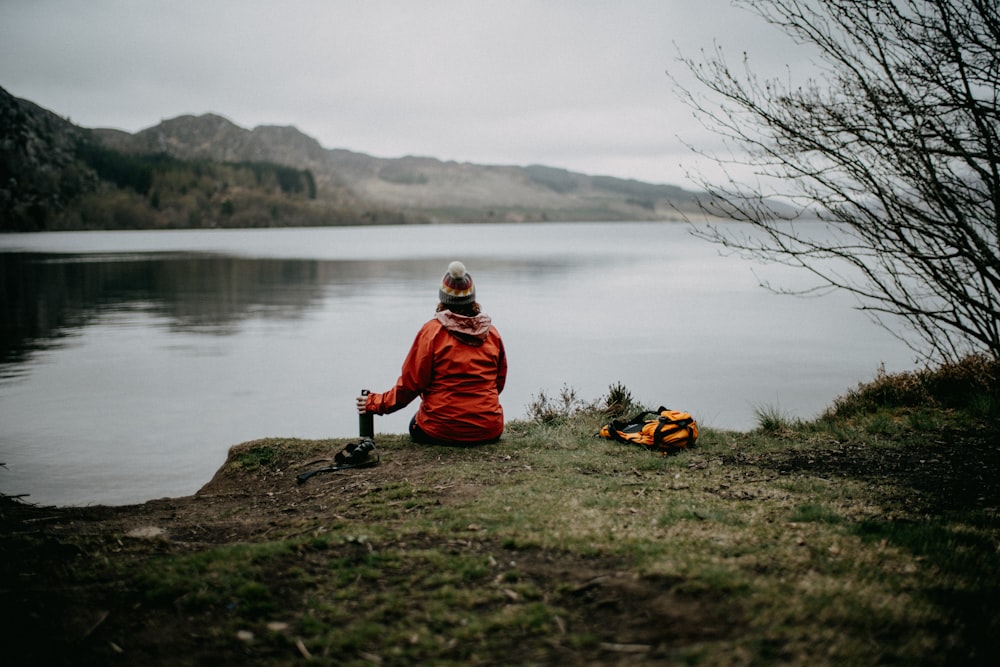 a person sitting on a hill by a body of water