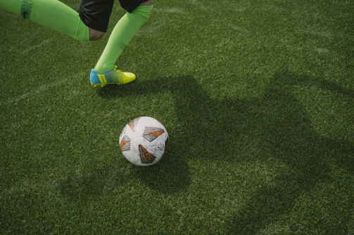 Close-up of a player’s boots striking the ball on a sunlit pitch.