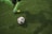 A close-up of soccer shoes kicking a ball on a grassy pitch.