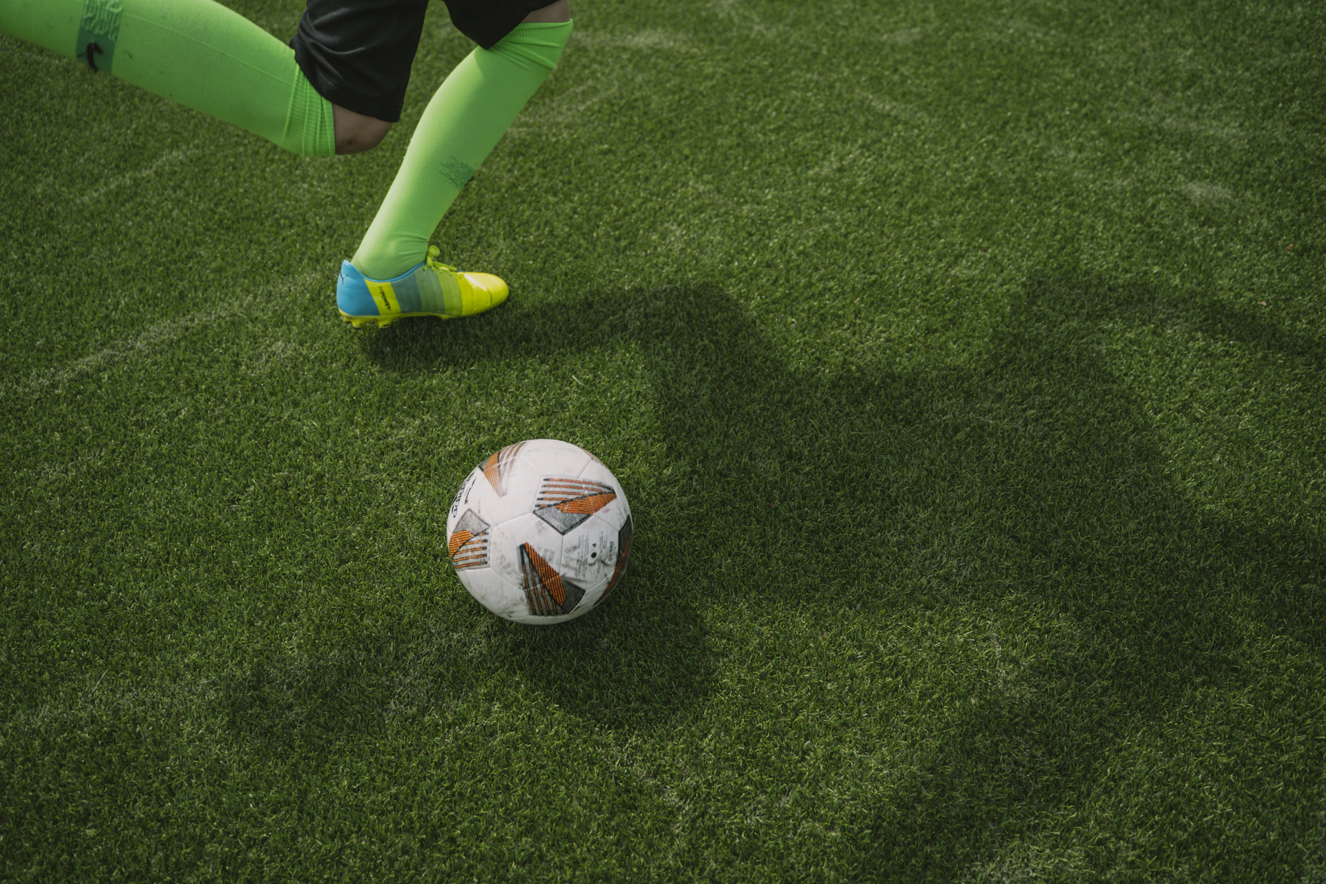 An artistic close-up of a player’s foot striking a ball, illustrated with smooth green gradients and crisp lines.