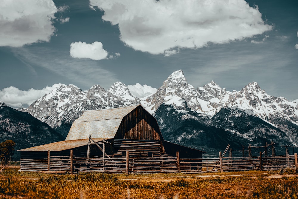 a barn in front of a snowy mountain range