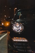 Bright LED car headlights glowing on a dark street at night