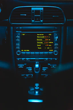 A sleek dashboard glowing softly in midnight navy and electric teal hues, with a technician adjusting satellite radio settings.