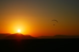 A vibrant ultralight aircraft soaring above a golden sunset sky.