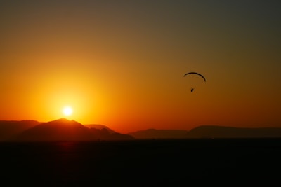 A vibrant ultralight aircraft soaring above a golden sunset sky.