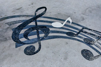A black treble clef and musical notes painted on a grey concrete surface