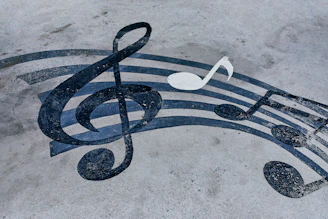 A black treble clef and musical notes painted on a grey concrete surface
