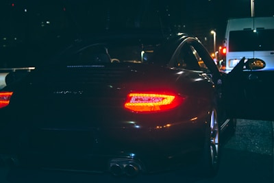 A polished stretch limousine with its door open, illuminated softly on a city street at night.