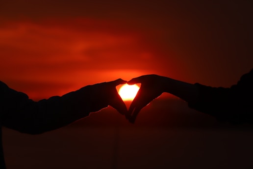 Two hands holding a heart-shaped constellation under a starry sky