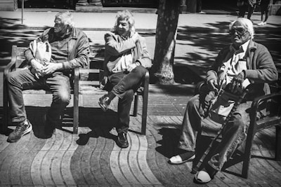 Outdoor scene of seniors enjoying a sunny day in the garden area, laughing and chatting on benches.