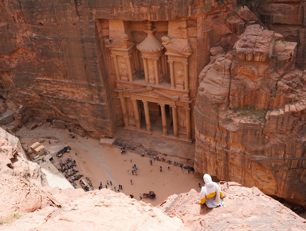 una persona seduta in una grotta con Petra sullo sfondo