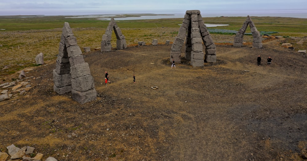 a group of people standing in a field with stone structures