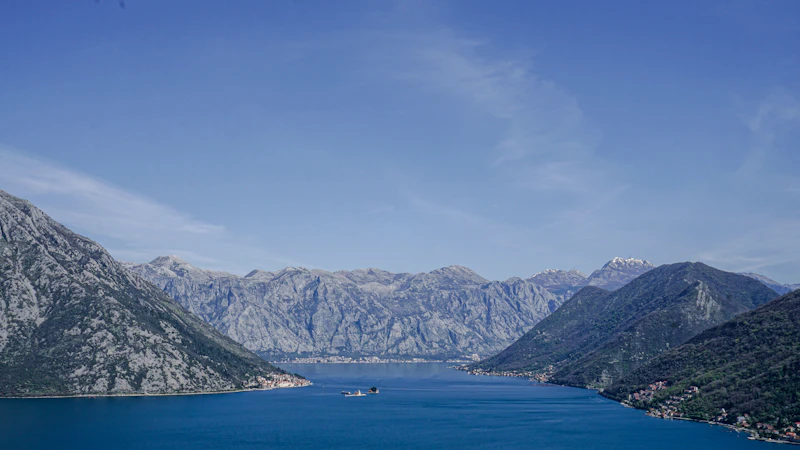 The wide Bay of Kotor between steep mountains, with a small island church on the water