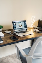 A modern workspace with a laptop and notebook on a wooden desk.