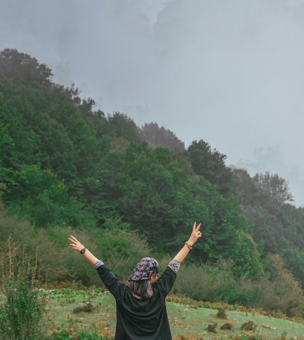 a person with the arms raised in front of a forest