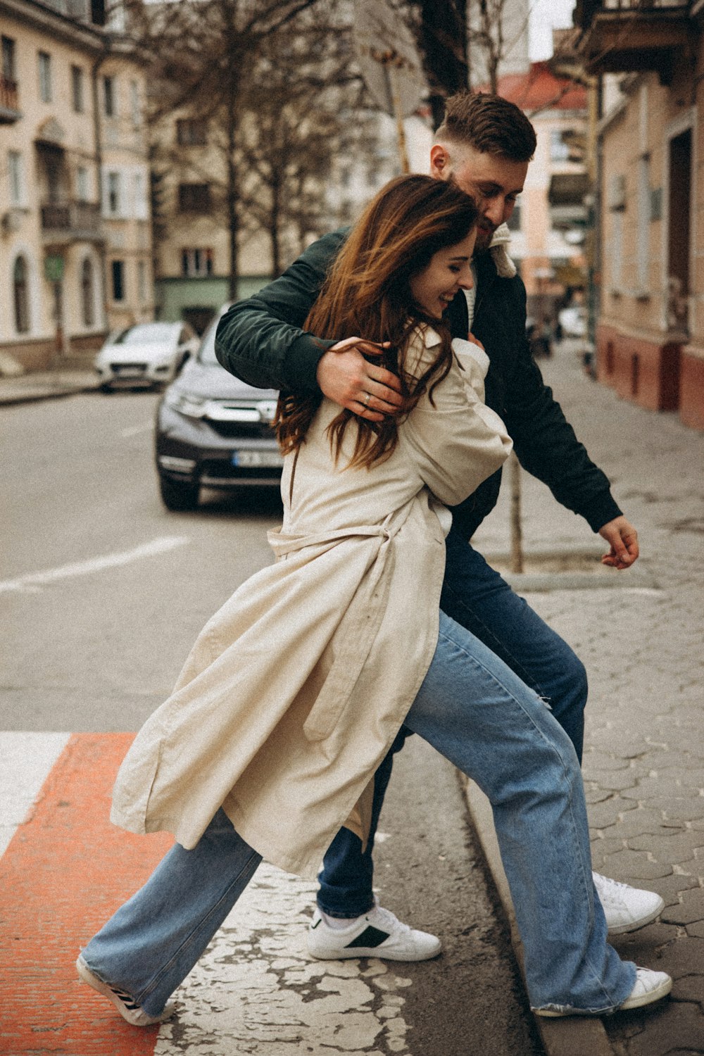 a man and woman kissing on a sidewalk