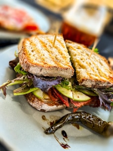 Freshly made golden veg sandwich with crisp lettuce and tomatoes served on a warm beige plate.