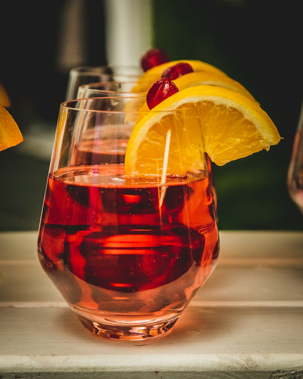 a glass of red liquid with a lemon slice on top