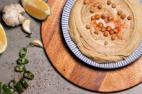 A vibrant bowl of creamy hommos topped with olive oil and sprinkled with paprika.