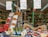 A vibrant market stall filled with a variety of fresh produce including asparagus, strawberries, and other fruits and vegetables. The setup includes wooden crates and baskets showcasing the colorful array of items. Price tags are prominently displayed in handwritten style on signs above the produce.