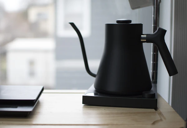Pouring hot water from a gooseneck kettle into a pour-over coffee cup