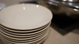 A set of white and red ceramic plates stacked neatly on a rustic wooden table.