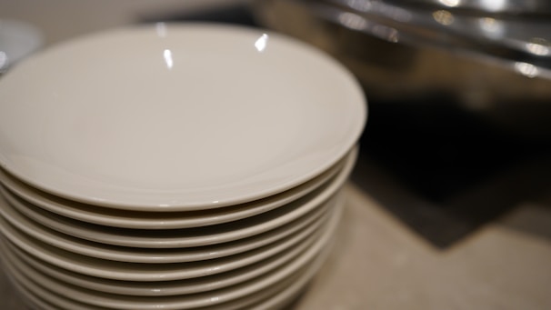 A set of modern white crockery plates and bowls arranged neatly on a kitchen countertop.