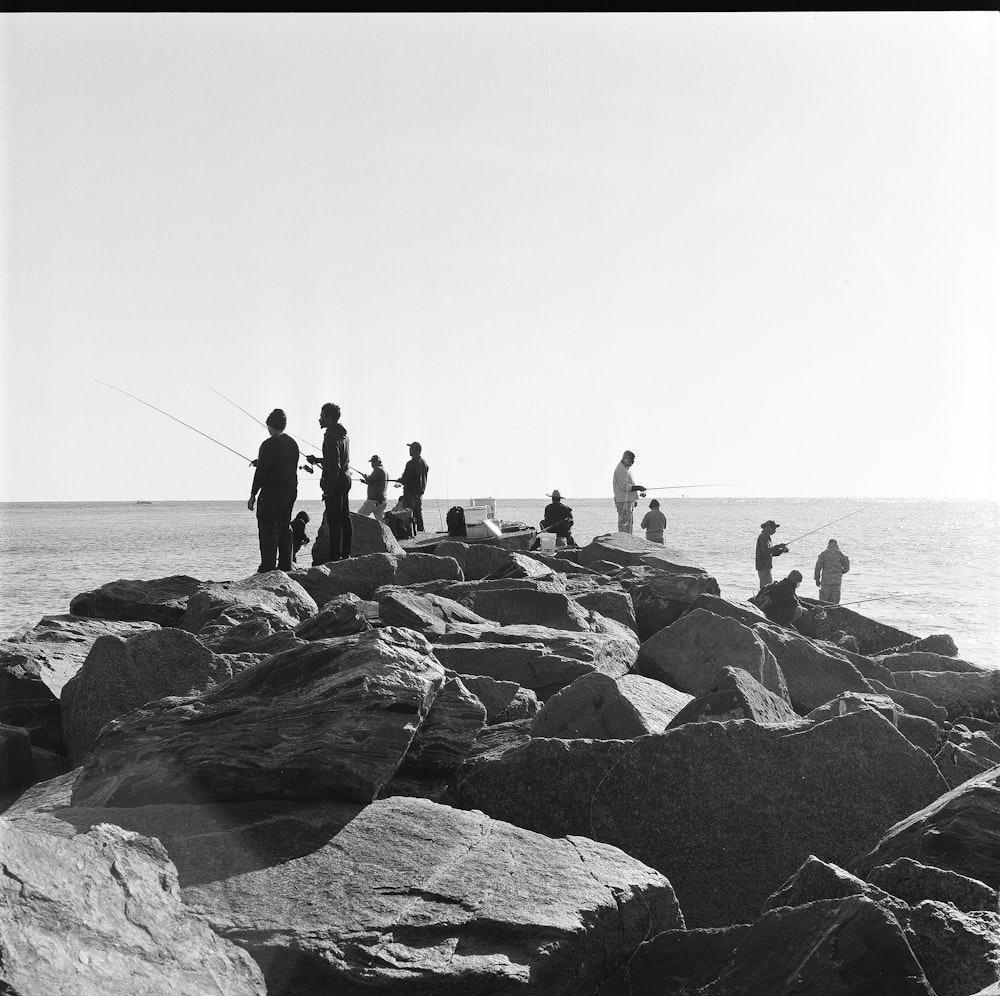 a group of people fishing on a rocky beach